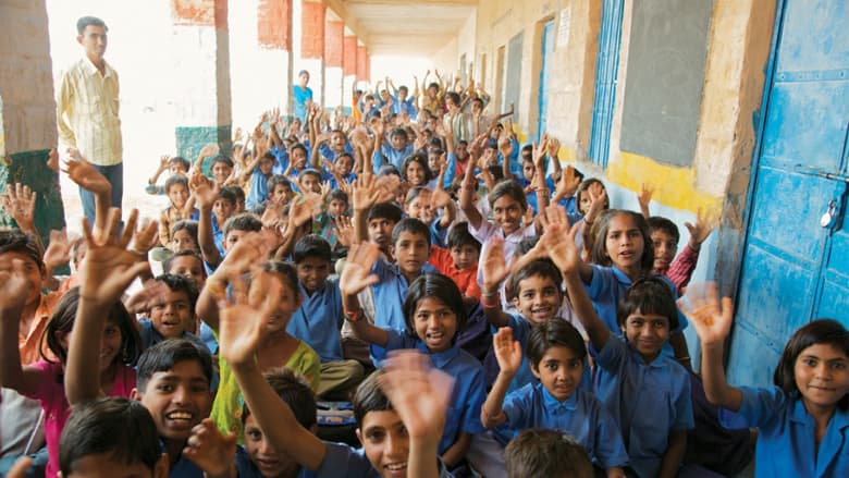 Children raising their hands in a classroom in rural India